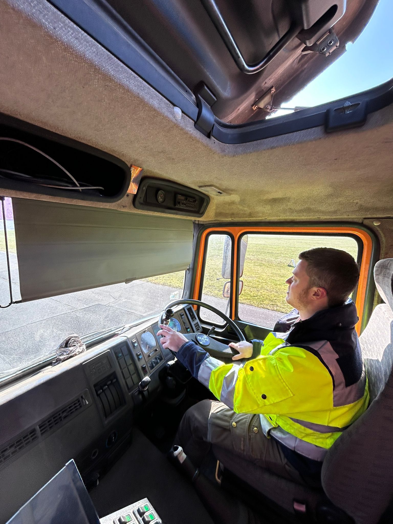 Fahrer in der Kabine des MAN-Kehrwagens mit Blick auf Rollweg und Vorfeld
