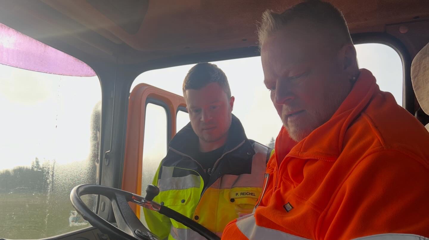 Zwei Helfer in der Kabine des Kehrwagens bei der Arbeit