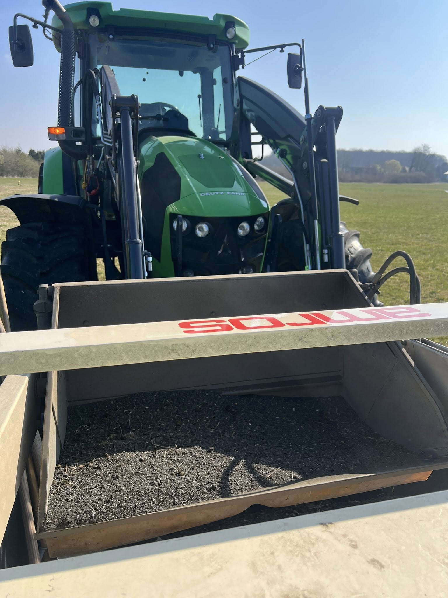 Traktor mit angefülltem Kehrgutbehälter – aufgesammeltes Material von Piste und Rollweg